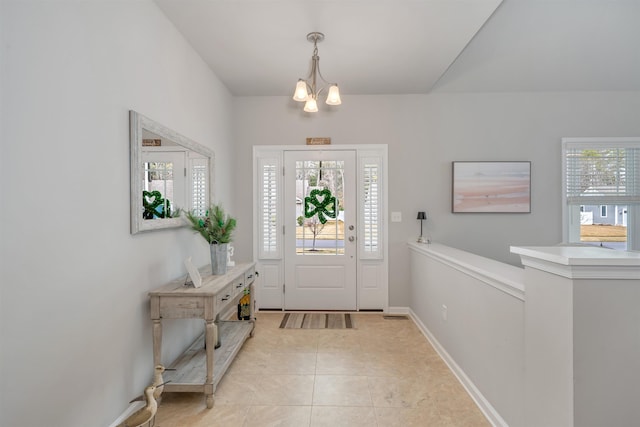 foyer entrance featuring a notable chandelier, light tile patterned floors, and baseboards