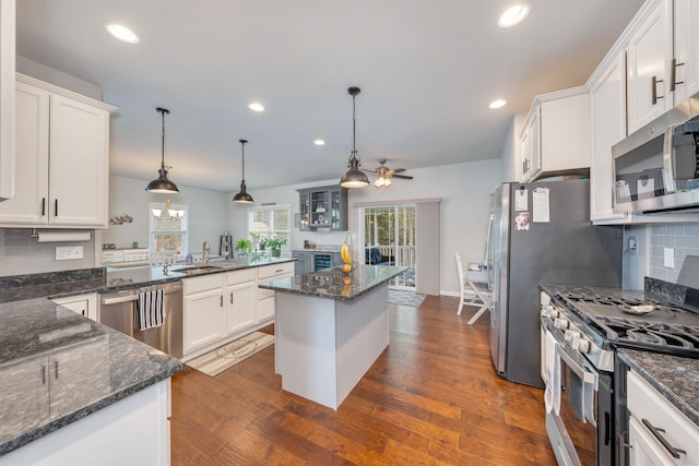 kitchen featuring dark wood finished floors, stainless steel appliances, a peninsula, white cabinets, and ceiling fan