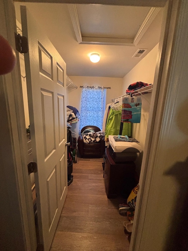 interior space featuring attic access, a raised ceiling, visible vents, and wood finished floors