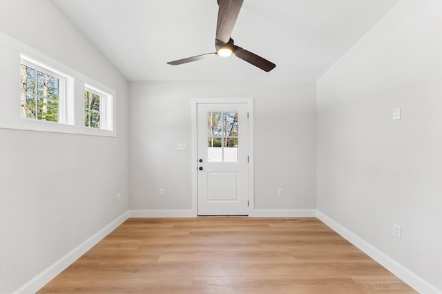 doorway featuring a wealth of natural light, light wood-style floors, a ceiling fan, and baseboards