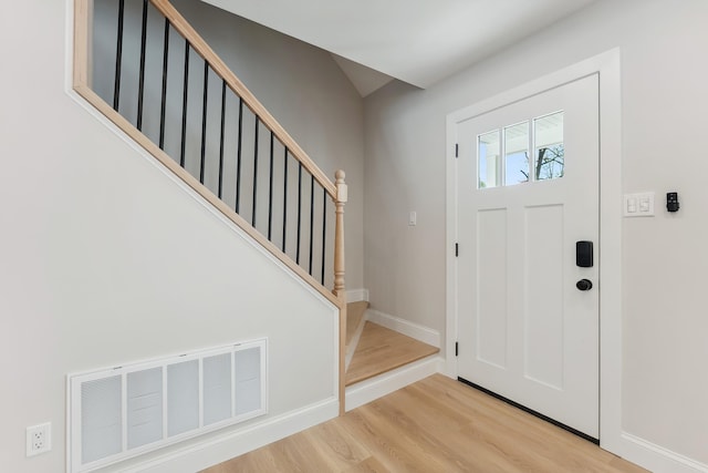 entryway with light wood finished floors, stairs, visible vents, and baseboards