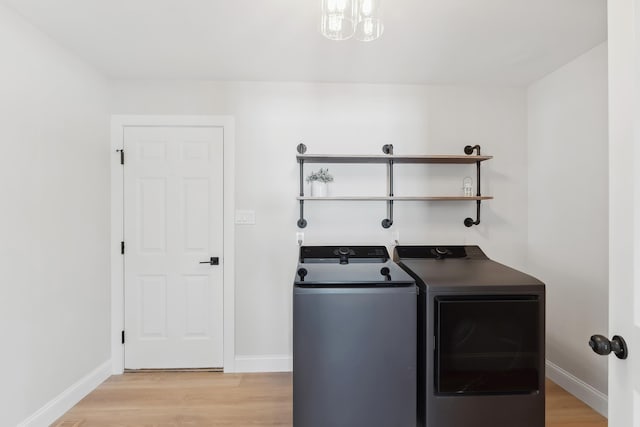 clothes washing area with baseboards, washer and dryer, laundry area, and light wood finished floors