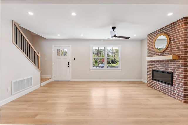 unfurnished living room featuring visible vents, ceiling fan, baseboards, light wood finished floors, and a fireplace