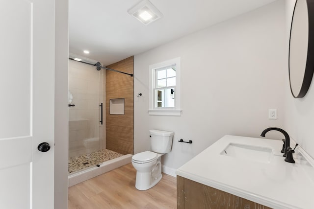 full bathroom featuring wood finished floors, toilet, a sink, baseboards, and a stall shower