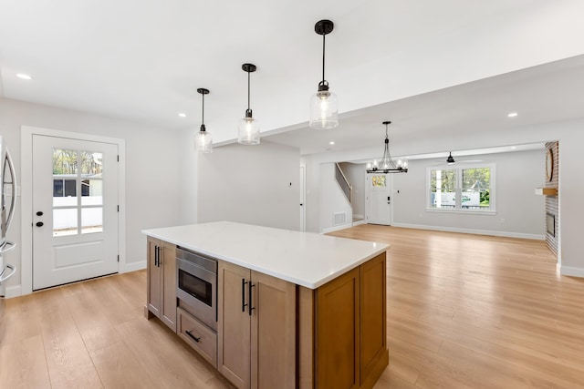 kitchen with light wood-type flooring, recessed lighting, a center island, and stainless steel microwave