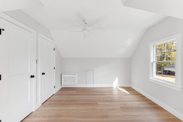 additional living space with a ceiling fan, baseboards, vaulted ceiling, and light wood-style floors