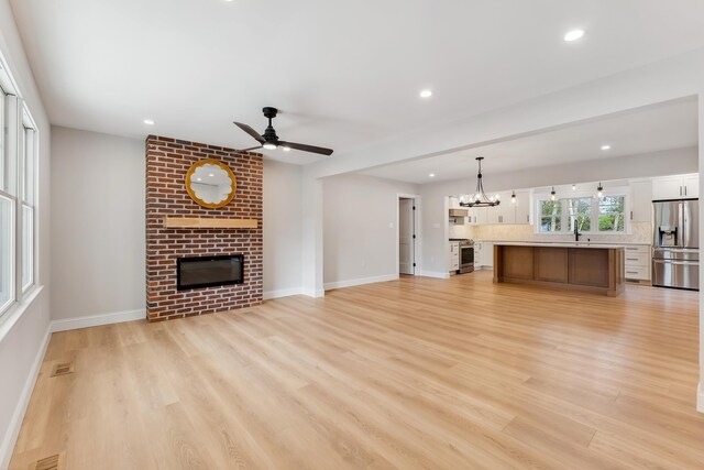 unfurnished living room featuring recessed lighting, light wood finished floors, and a brick fireplace
