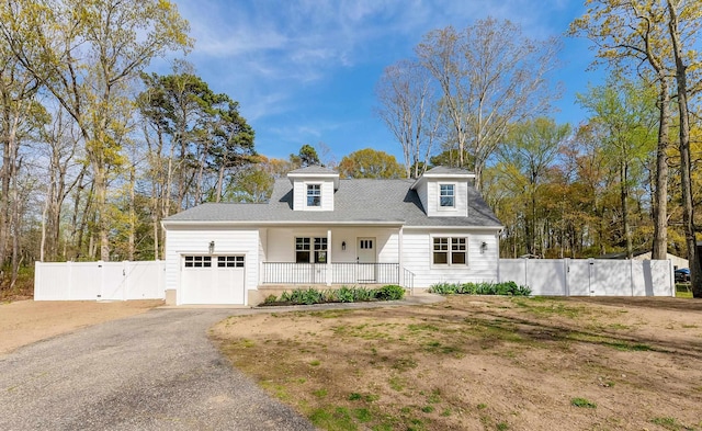 cape cod-style house with a gate, covered porch, fence, aphalt driveway, and an attached garage