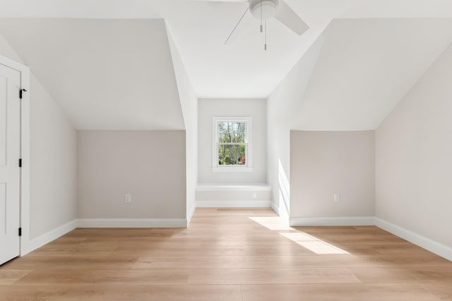 bonus room with vaulted ceiling, a ceiling fan, light wood-style flooring, and baseboards