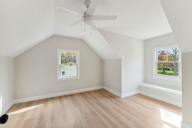 additional living space with lofted ceiling, a wealth of natural light, light wood-type flooring, and a ceiling fan