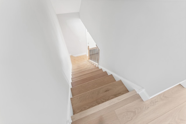 stairway with wood finished floors and baseboards