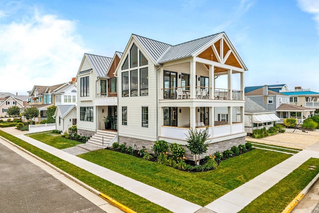 144 89th St, Stone Harbor, NJ 08247 - view of front of house featuring a standing seam roof, a balcony, a residential view, a metal roof, and a front yard