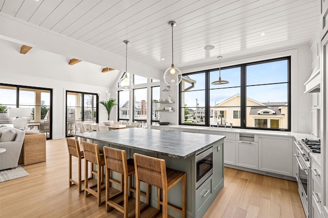 144 89th St, Stone Harbor, NJ 08247 - kitchen with stainless steel microwave, wood ceiling, light wood finished floors, open floor plan, and a breakfast bar area
