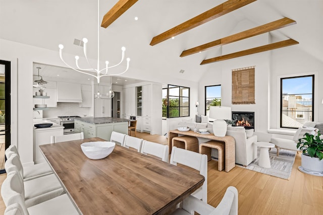 144 89th St, Stone Harbor, NJ 08247 - dining room with high vaulted ceiling, beam ceiling, a glass covered fireplace, light wood-style floors, and a chandelier