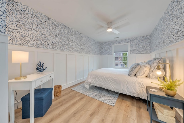 202 Osprey Dr Unit 202, Cape May Court House, NJ 08210 - bedroom with wainscoting, a decorative wall, wood finished floors, wallpapered walls, and a ceiling fan