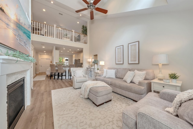 202 Osprey Dr Unit 202, Cape May Court House, NJ 08210 - living room with light wood-style floors, ceiling fan, a glass covered fireplace, recessed lighting, and a towering ceiling