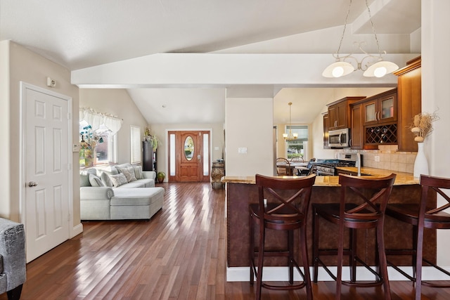 kitchen featuring a healthy amount of sunlight, stainless steel appliances, pendant lighting, vaulted ceiling, and decorative backsplash