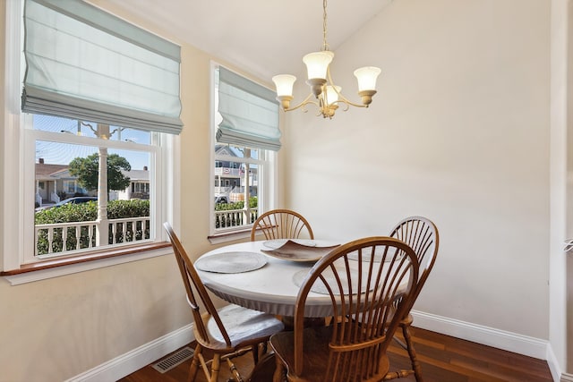 dining room with a chandelier, vaulted ceiling, a wealth of natural light, and dark wood-type flooring