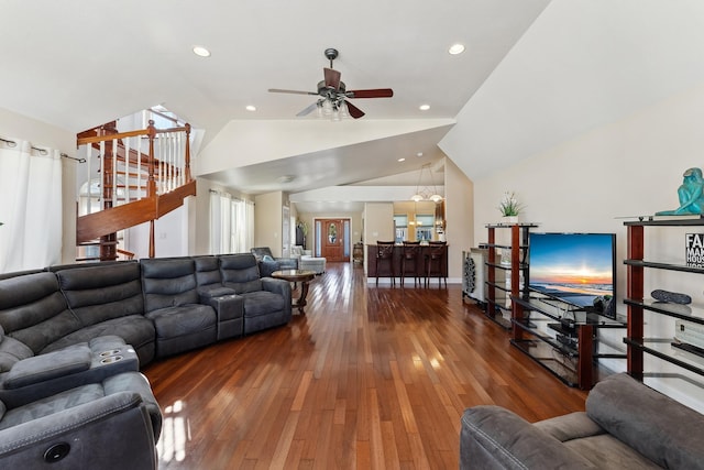 living room with ceiling fan with notable chandelier, dark hardwood / wood-style flooring, and vaulted ceiling