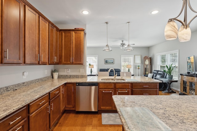 kitchen with dishwasher, decorative light fixtures, light hardwood / wood-style floors, sink, and light stone counters