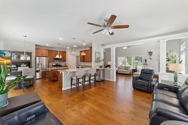 living room featuring ceiling fan, dark hardwood / wood-style floors, and ornate columns