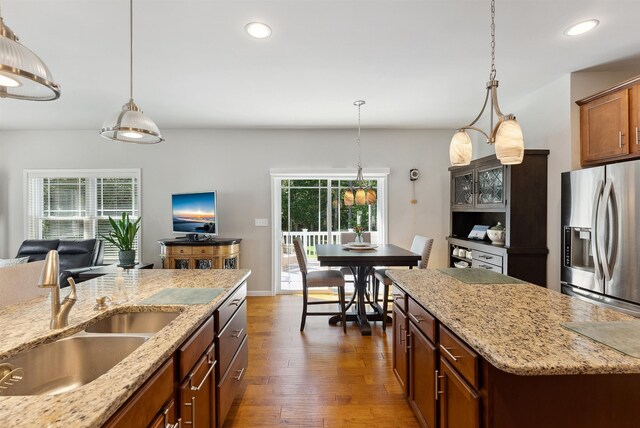 kitchen featuring light stone countertops, sink, stainless steel fridge, and a center island