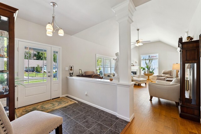 entrance foyer with decorative columns, ceiling fan with notable chandelier, dark wood-type flooring, and lofted ceiling