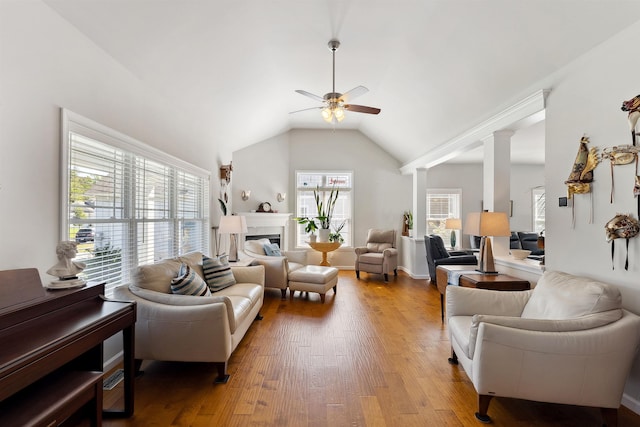 living room featuring decorative columns, a wealth of natural light, ceiling fan, and light wood-type flooring