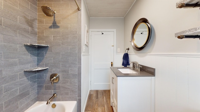 bathroom with hardwood / wood-style floors, vanity, and tiled shower / bath