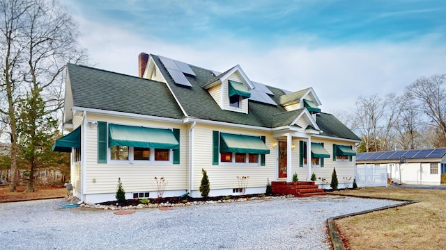 new england style home with a front yard and solar panels