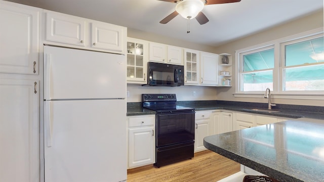 kitchen with black appliances, white cabinetry, sink, and light hardwood / wood-style flooring