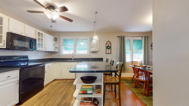 kitchen featuring black appliances, a kitchen breakfast bar, sink, light hardwood / wood-style flooring, and white cabinetry