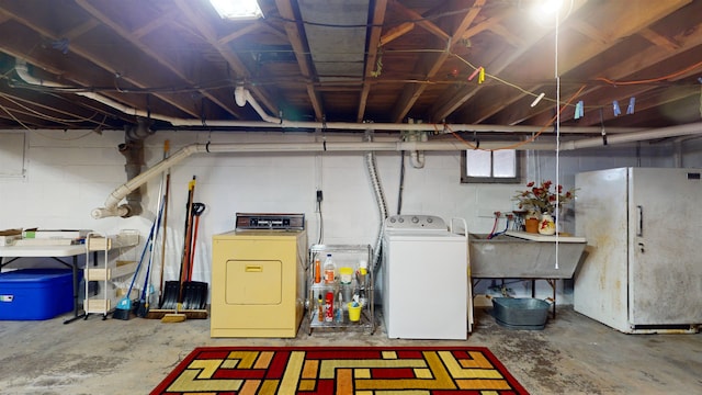 basement featuring washing machine and dryer and white fridge