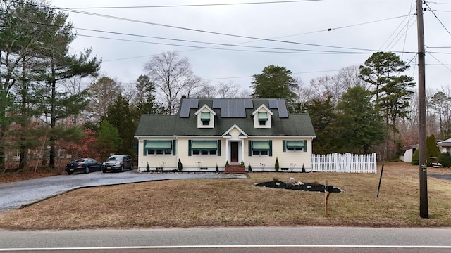 cape cod-style house with solar panels and a front lawn