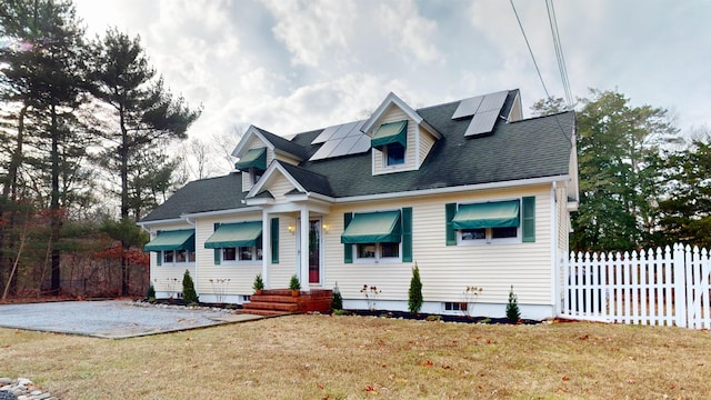 cape cod home with solar panels and a front lawn