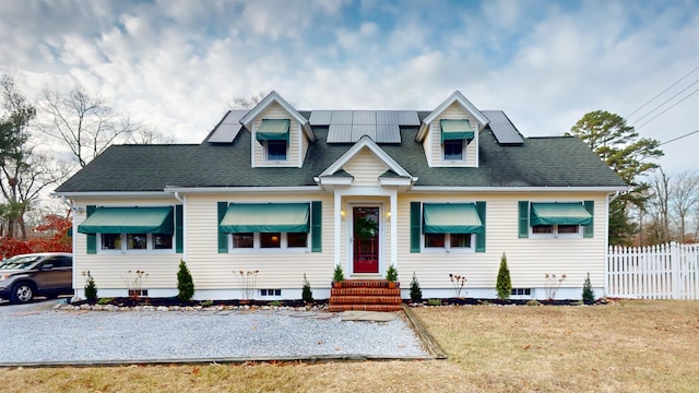 view of front of property with a front yard and solar panels