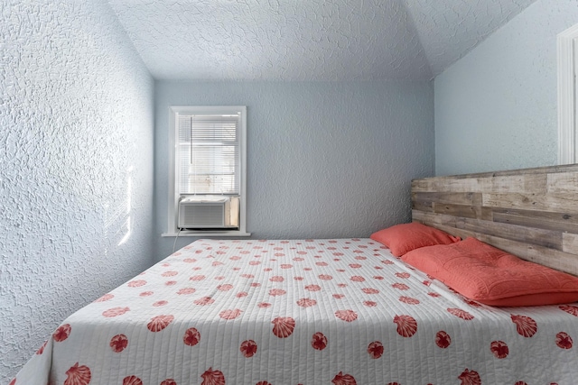 bedroom featuring cooling unit, lofted ceiling, and a textured ceiling