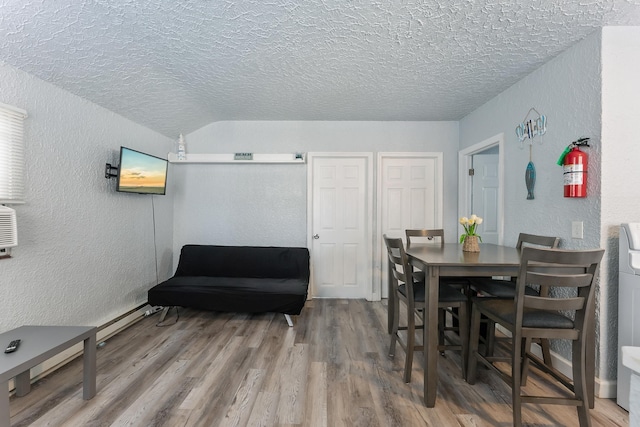 dining space with a baseboard heating unit, hardwood / wood-style flooring, and a textured ceiling