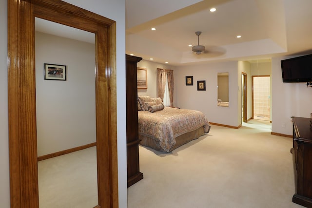 bedroom with a raised ceiling, ceiling fan, and light colored carpet