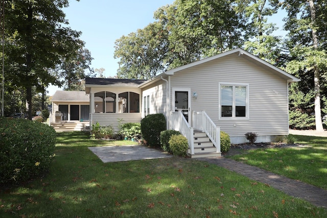 view of front of home with a sunroom, a patio, and a front lawn