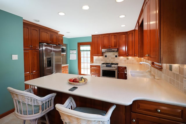 kitchen featuring a kitchen bar, high end appliances, kitchen peninsula, and sink