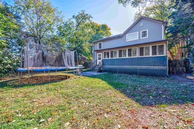 back of house featuring a sunroom, a trampoline, and a yard