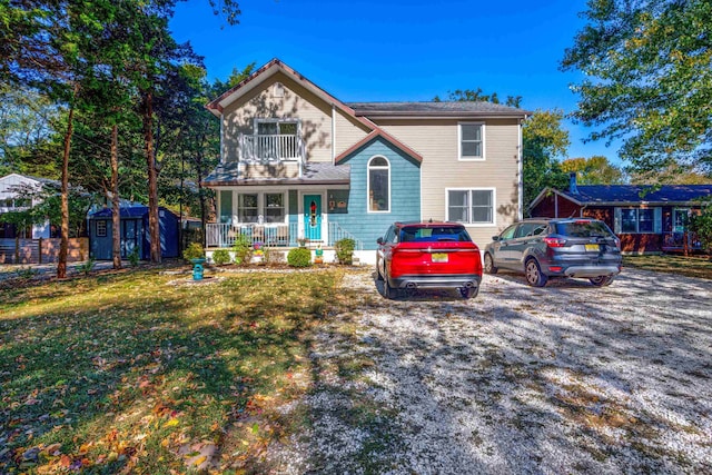 view of front of house with a balcony, a front lawn, a porch, and a storage shed