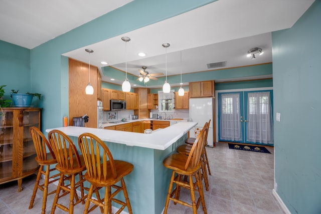 kitchen with a kitchen bar, sink, white fridge, and hanging light fixtures