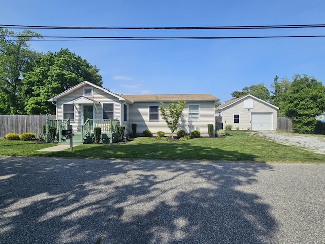 view of front facade with a detached garage, driveway, fence, and an outdoor structure
