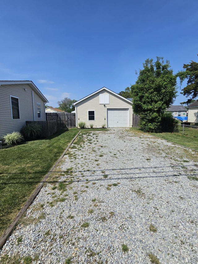 view of front of house featuring fence, a detached garage, a front yard, an outdoor structure, and driveway