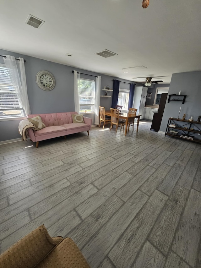 living area with ceiling fan, wood finished floors, and visible vents