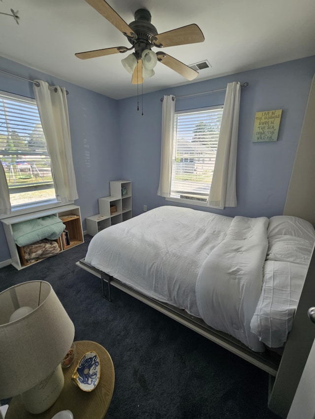 carpeted bedroom with a ceiling fan and visible vents
