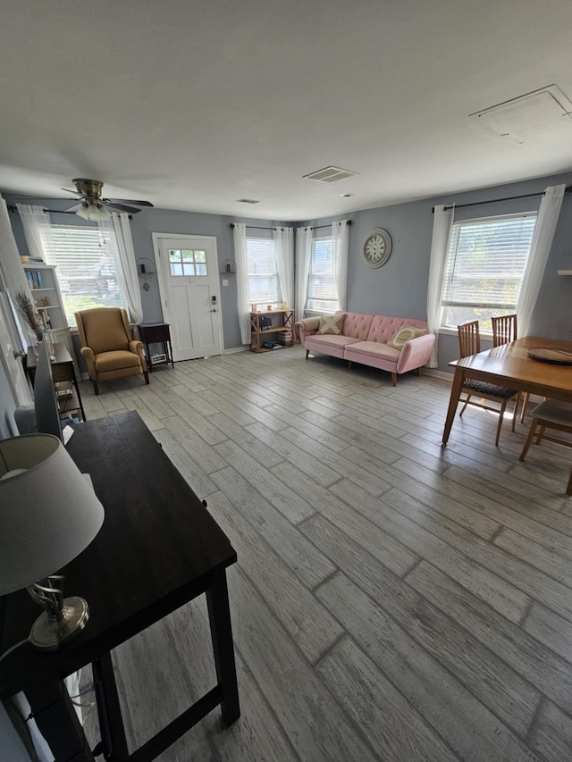 living room with light wood-style floors, ceiling fan, and visible vents