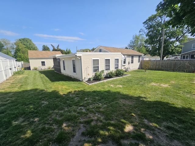 rear view of property with a fenced backyard and a yard